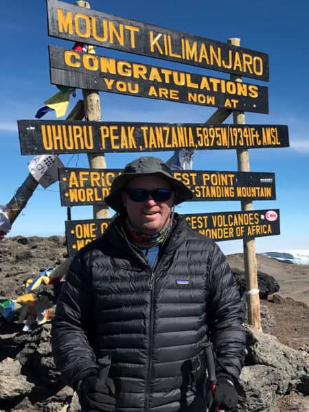 hiker in front of mount kilimanjaro sign